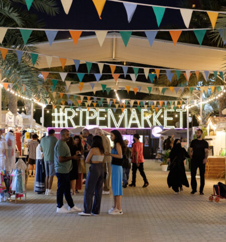 Shoppers exploring illuminated stalls at The Ripe Market – Academy Park Dubai during an evening event.