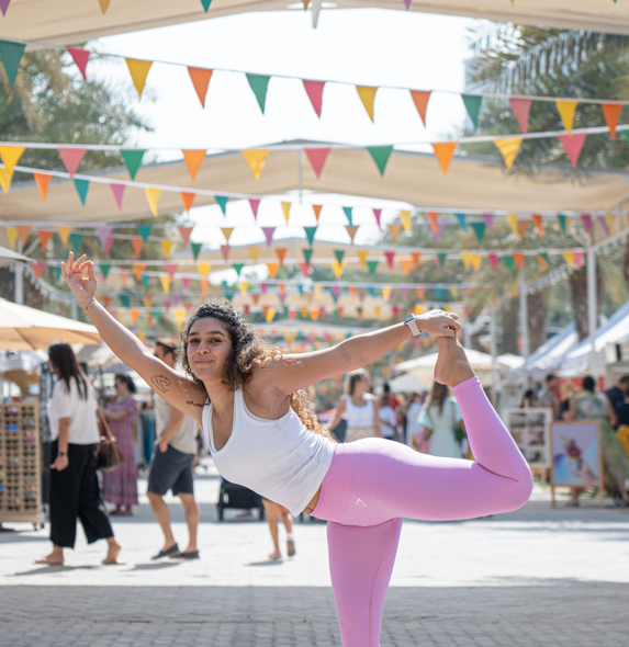 Girl is doing a yoga pose at the Walkway of The Ripe Market - Academy Park Dubai.