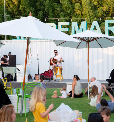 Families relaxing on the lawn during live music at The Ripe Market – Academy Park Dubai.