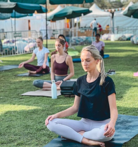 Participants practicing outdoor yoga on the lawn at The Ripe Market – Academy Park Dubai wellness session.